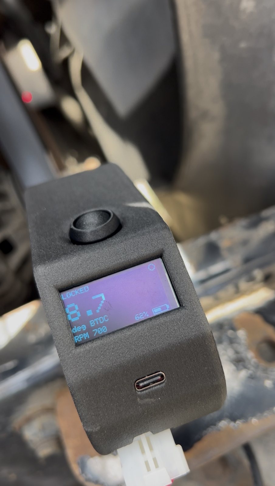 Timing Buddy clamped to a running engine, screen reading 8.7 degrees BTDC at 700 RPM