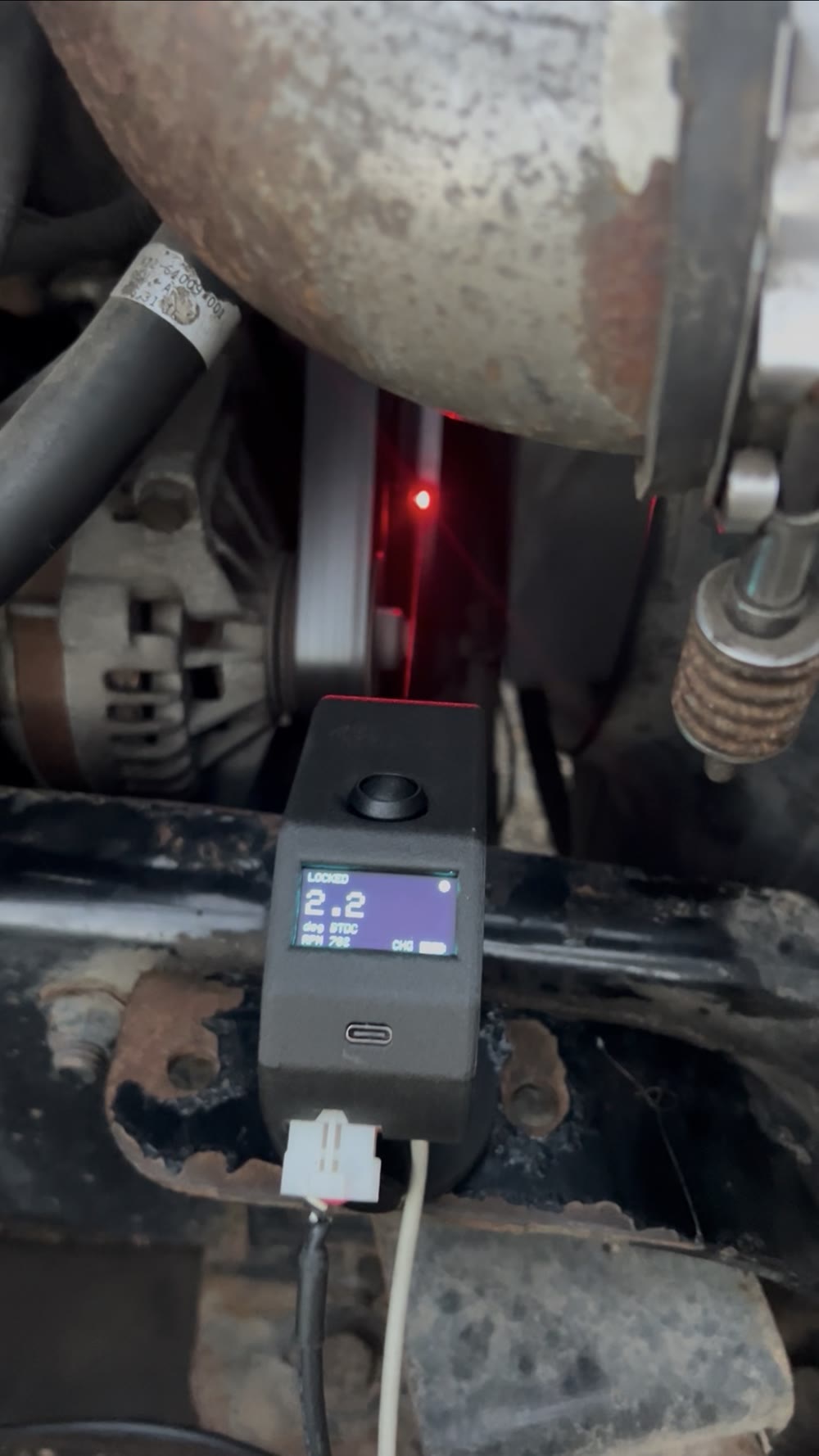 Timing Buddy on the running engine with its red laser lit on the crank target, screen locked at 2.2 degrees BTDC